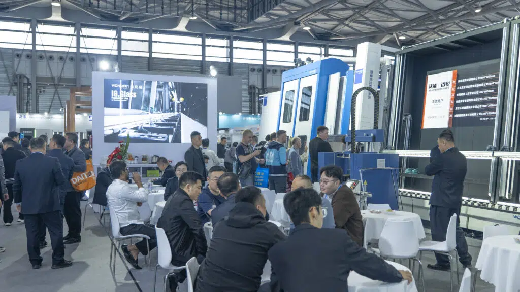 Visitors at the WONDEC booth during China Glass 2026 beside an insulating glass production line